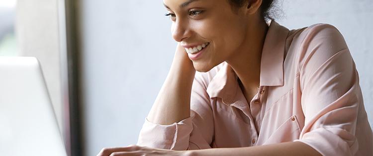 Foto de una mujer de 20 y tantos mirando una computadora portátil