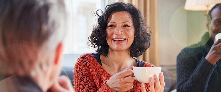 Una mujer sonriendo que sostiene una taza de té en sus manos.