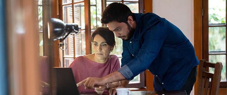 Un hombre y una mujer frente a un computador. El hombre señala algo en la pantalla.