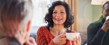 Una mujer sonriendo que sostiene una taza de té en sus manos.
