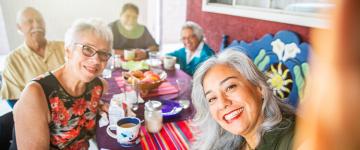 Una mujer con otras cuatro personas sentadas alrededor de una mesa que posan para una foto.