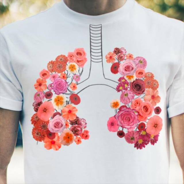 Persona vistiendo una camiseta con un gráfico de unas flores rosadas formando unos pulmones.